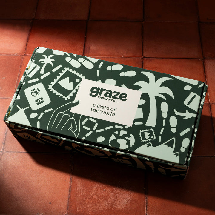 a closed graze snack box filled with various packaged snacks, displayed on a tiled surface