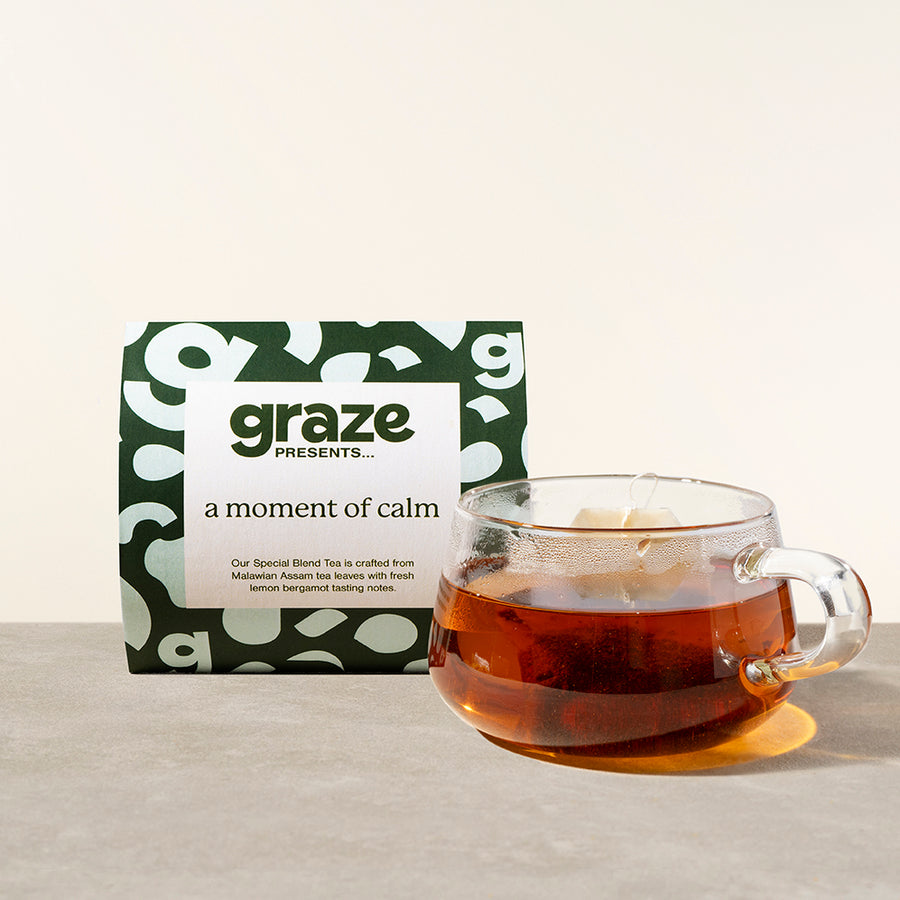 a package of graze 'a moment of calm' tea next to a clear mug of a teabag in tea